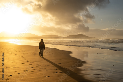Φωτογραφία Person walks along the serene Famara Beach in Lanzarote, leaving footprints in the sand