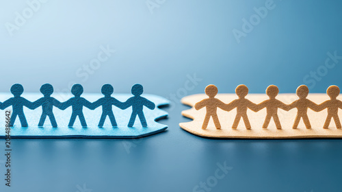Paper cutout teams standing on separate puzzle pieces reaching across a gap to bridge connection and collaboration, symbolizing teamwork, inclusion and partnership in business and community