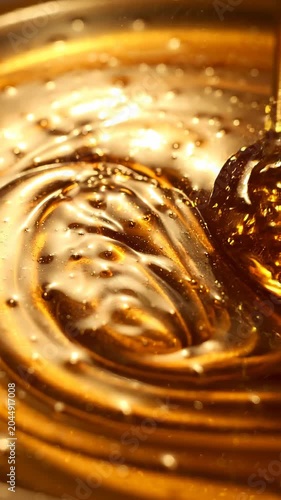 Viscous golden honey flows, creating mesmerizing swirls with tiny air bubbles captured in its rich texture, evoking a sense of pure, natural sweetness.