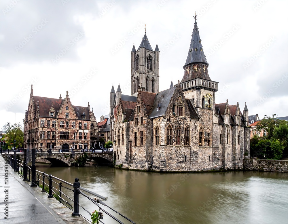 Fototapeta premium A serene river flows gently past a medieval church and buildings