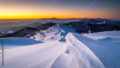 Snow-covered mountain ridge under vibrant sunrise sky