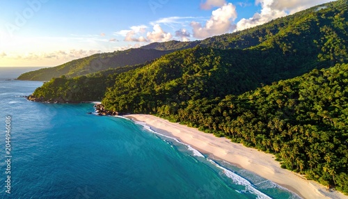 Lush green mountains meet a pristine white beach and turquoise ocean