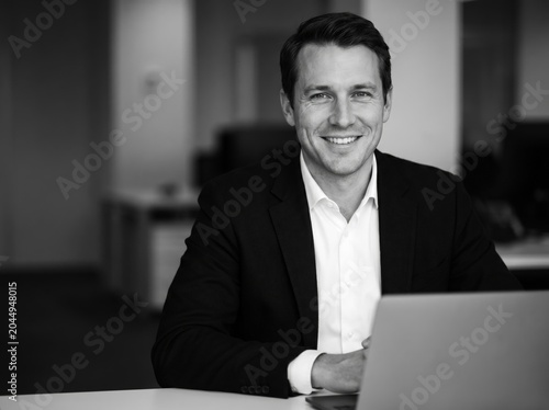 Smiling man in suit leaning on table