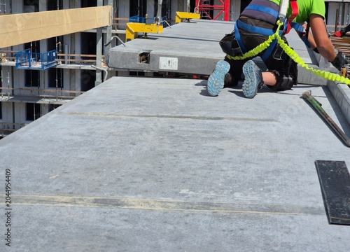 Billede på lærred Rear view of a worker in proper PPE and fall protection installing a precast balcony panel