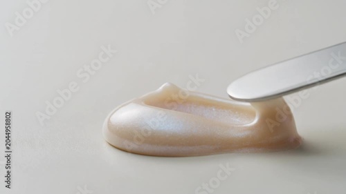 Close-up of Spatula Spreading Pearlescent Cream Illustrating Smooth Application and Luxurious Product Texture.
