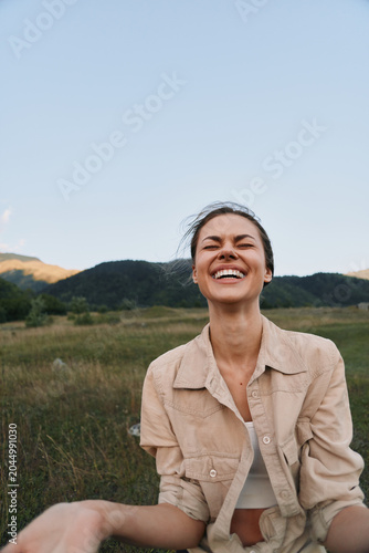 Foto Woman outdoors, smiling with eyes closed, sunlit field background, casual jacket