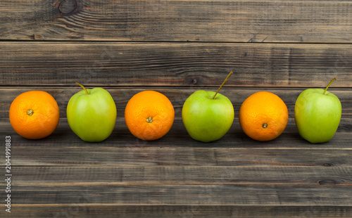 Apples and oranges on a wooden background.