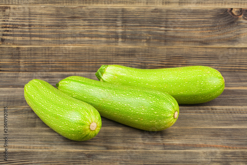Green zucchini on a wooden background.