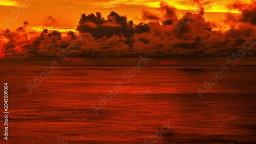 Dramatic Orange Sunset Over Calm Ocean With Dark Clouds