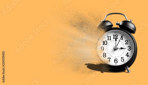 Bild auf Leinwand Black alarm clock disintegrating into dust on an orange background with copy spa