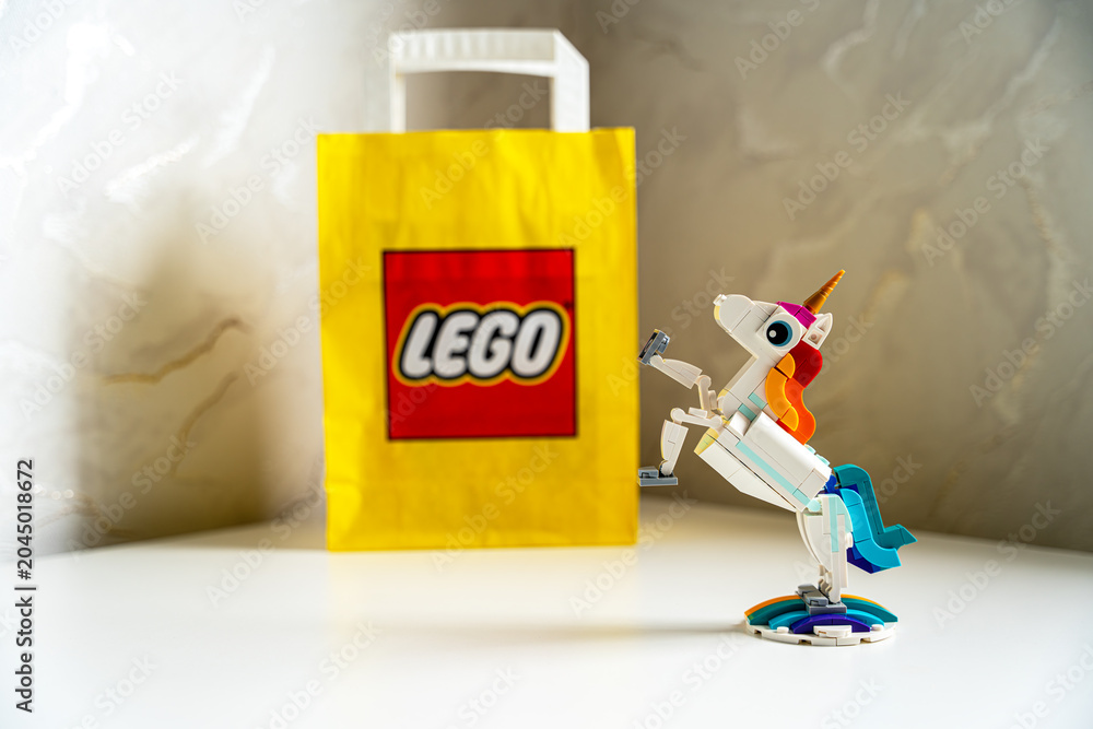 Obraz premium LEGO Creator 3-in-1 Magical Unicorn on white table with yellow LEGO paper bag. A built LEGO Creator Magical Unicorn toy figure stands in a rearing pose on a rainbow base.