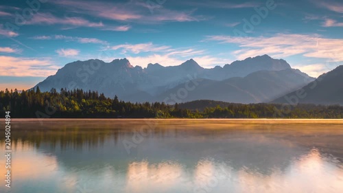 Sunrise Over Calm Lake and Forest With Mountain Range