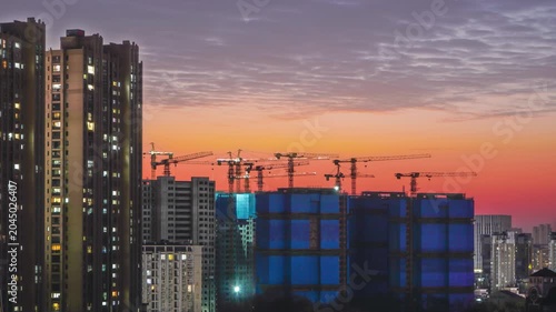 Urban skyline with residential towers and construction cranes at sunset