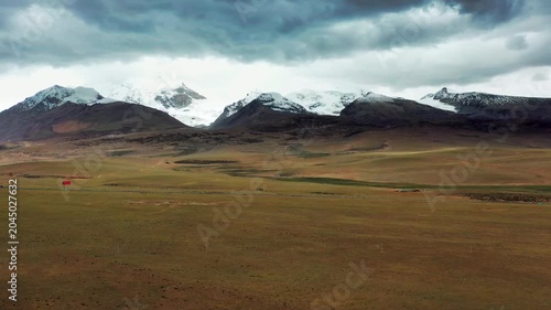 Barren Plateau and Snow Capped Mountains Under Dramatic Cloudy Sky