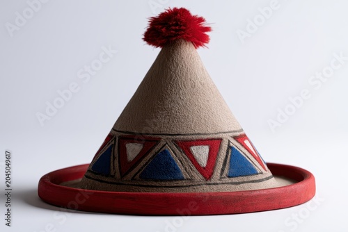 Conical Folkloric Hat with Red Pompom and Geometric Triangles, isolated on white background