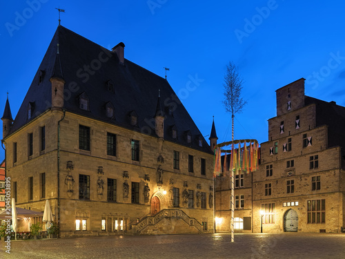 Osnabruck, Germany. Historical Market Square with Old Town Hall, Stadtwaage (city weighhouse or weighing house) and erected Maypole in dusk.