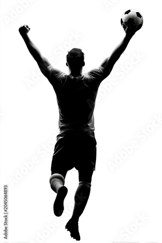 Silhouette of a soccer player jumping with arms raised holding a ball celebrating victory or goal achievement in dramatic backlight