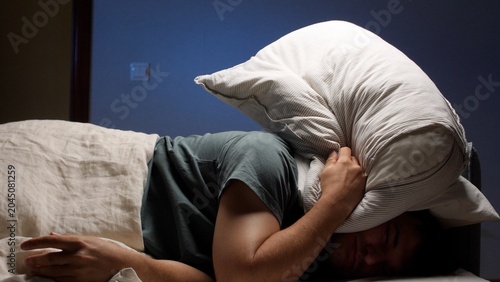 Photos Sleepless person lying in bed, feeling stressed and restless in a dark bedroom,