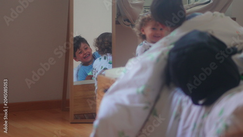 Foto Toddler investigating moving duvet on bed before older sibling appears during pl