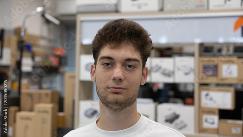 portrait of a young caucasian man looking directly at camera with neutral expression in a bright store background