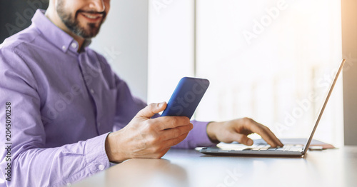 Fotografie A man is seated at a desk with a laptop open in front of him
