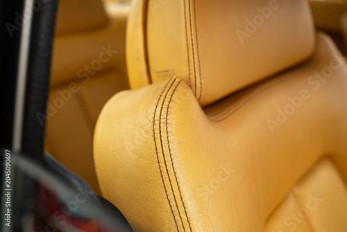 Close-up view of premium black twin stitching on a bright saffron yellow leather seat bolster in a clean automotive interior