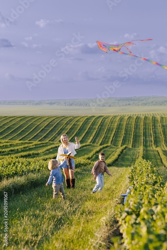 Happy children running with mother flying kite