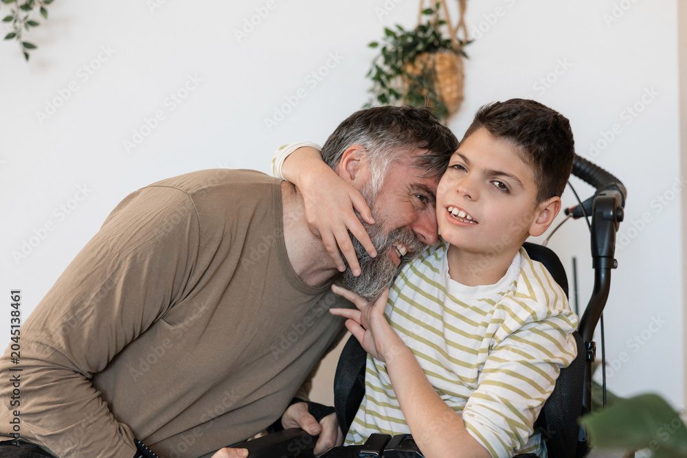 Obraz premium Father and son embracing in wheelchair with cerebral palsy