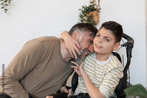Father and son embracing in wheelchair with cerebral palsy