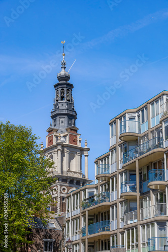 View of Amsterdam cityscape featuring historic architecture along Zwanenburgwal canal under a clear blue sky.