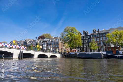 A picturesque view of Amsterdam's canals and historic buildings under a clear blue sky, highlighting the city's charming architecture and vibrant atmosphere.