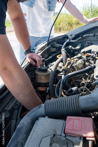 Foto Man checking car engine for problems on a hot sunny day during a roadside breakd