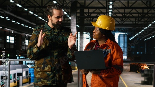 Photography Engineer and military officer reviews production to support wartime industry in heavy industry factory, Diverse workforce ensuring defense logistics and national war effort in large-scale plant