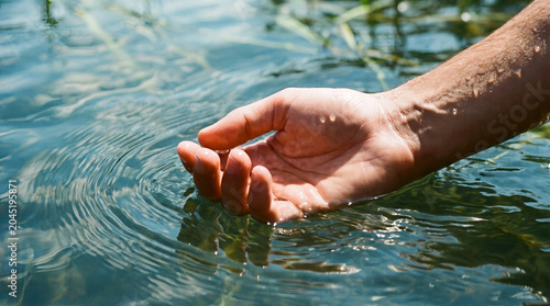 Man's hands reaching above clear swimming pool water with splash, summer relaxation concept