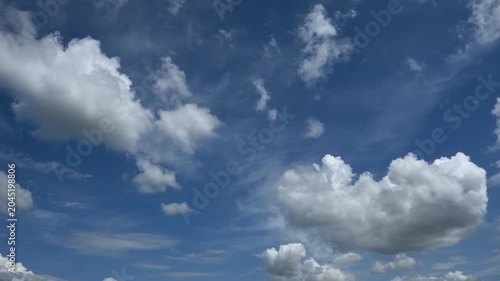 Time lapse of white cumulus clouds building and drifting through a bright blue summer sky
