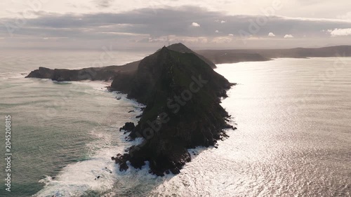 Aerial view of Cape Point, Cape of Good Hope near Cape Town, South Africa. Camera sweeps along ridge and path, showing upper and lower lighthouses, waves pound rocky shore.