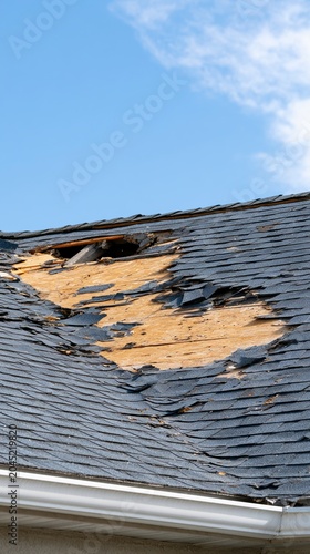 Residential roof showing torn shingles and exposed decking