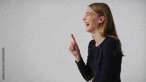 Young woman in dark blue dress thinking and pointing finger against white background medium shot