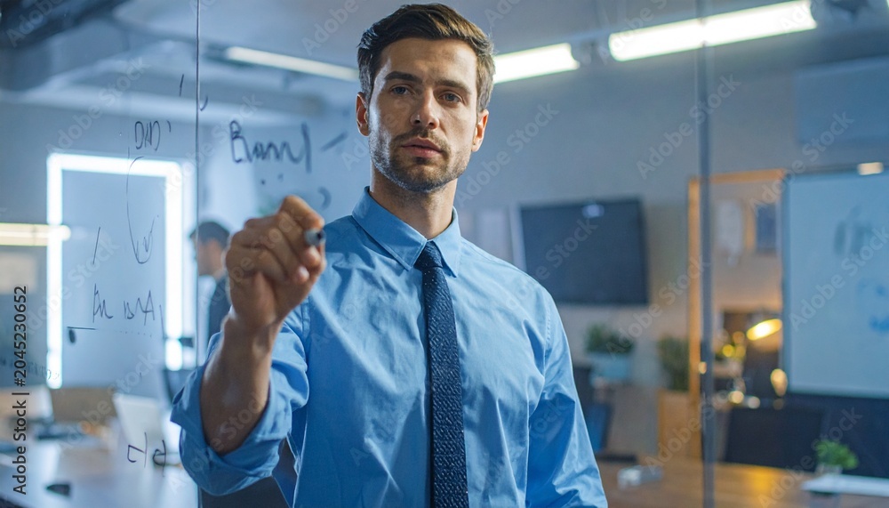Fototapeta premium Young Professional Businessman Planning and Writing on Glass Wall in Modern Office