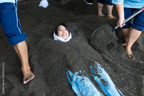 Obraz na plátně Smiling woman buried in volcanic black sand bath for spa