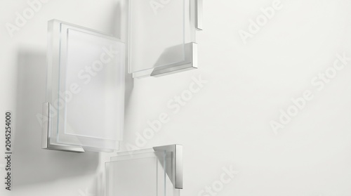 Three floating rectangular glass frames with metallic corner brackets arranged on a clean white background wall