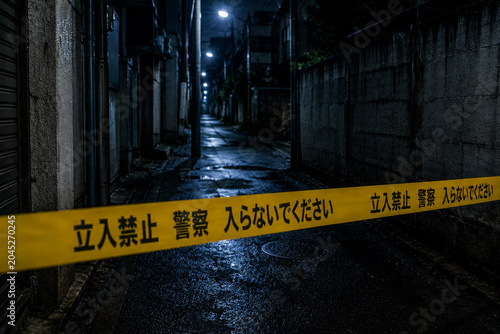 立入禁止テープで封鎖された深夜の路地　捜査・犯罪イメージ