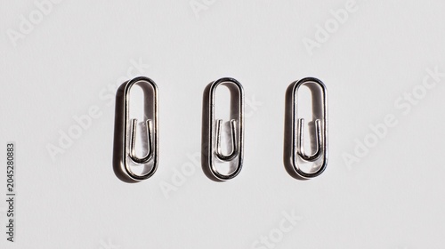 Silver safety pins aligned on white top down