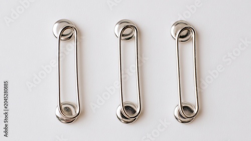 Silver safety pins aligned on white top down