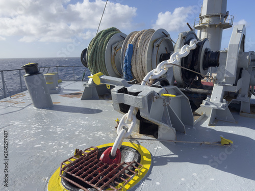 Forecastle deck of a cargo ship with complete mooring and anchoring system. Anchor chain led through chain stopper to windlass gypsy wheel. Mooring winch with professionally stowed mooring lines 