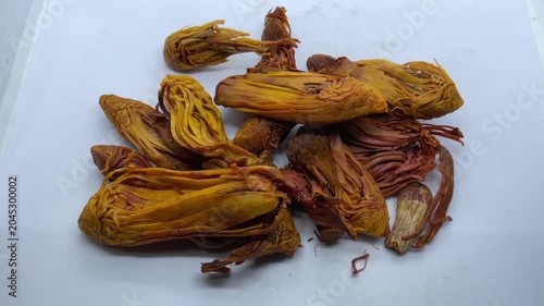 pile of dried Rampatri (Wild Mace) pieces isolated on a clean white background. The image showcases the intricate, reticulated, and lacy texture of these orange-brown whole spices. 