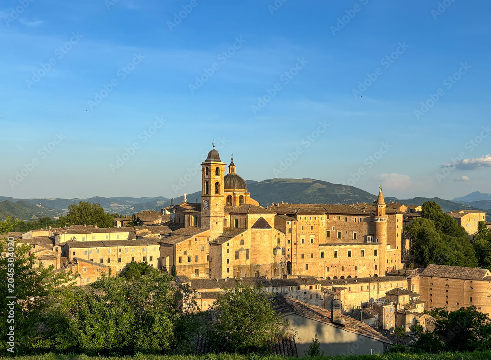 Fototapeta premium Panoramic aerial view of Urbino’s historic old town at golden hour, showcasing its Renaissance architecture, iconic landmarks, and the rolling hills of the Marche region, Italy.