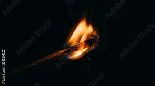Burning wooden match stick with bright flame on dark background
