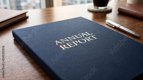 Annual report book on wooden desk with pen and coffee cup