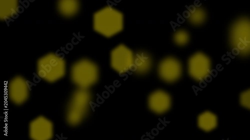 Yellow hexagonal bokeh shapes and gold spots on dark background. Dynamic pattern for backgrounds, web design, and festive designs.